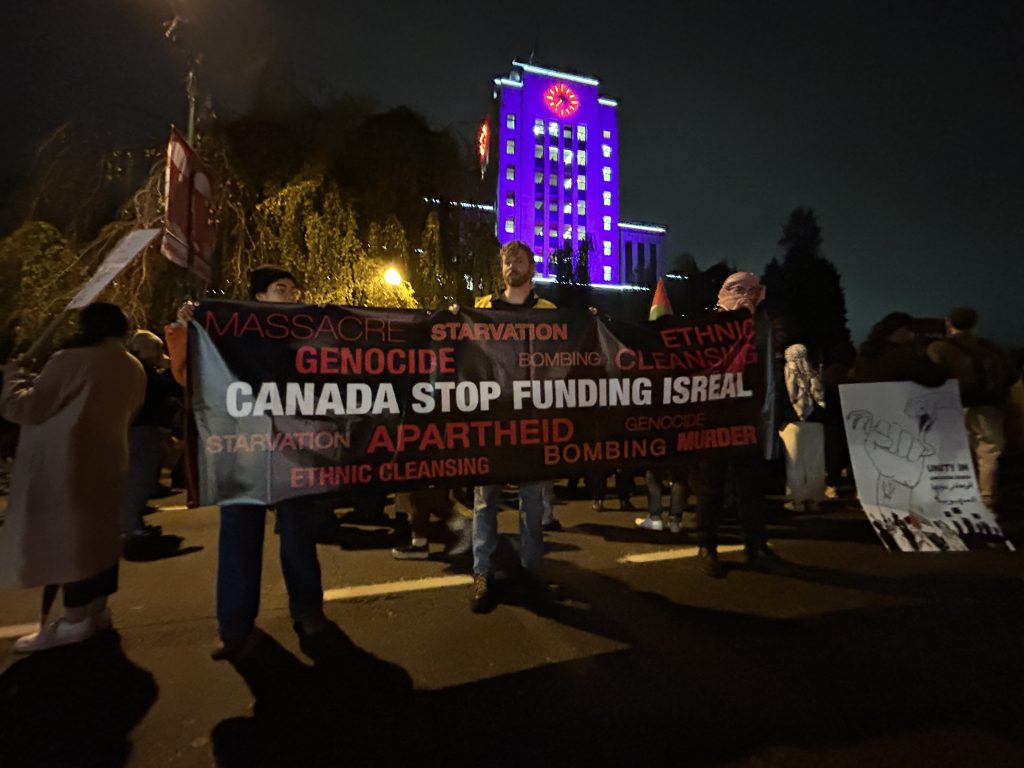 People hold up a sign outside Vancouver City Hall