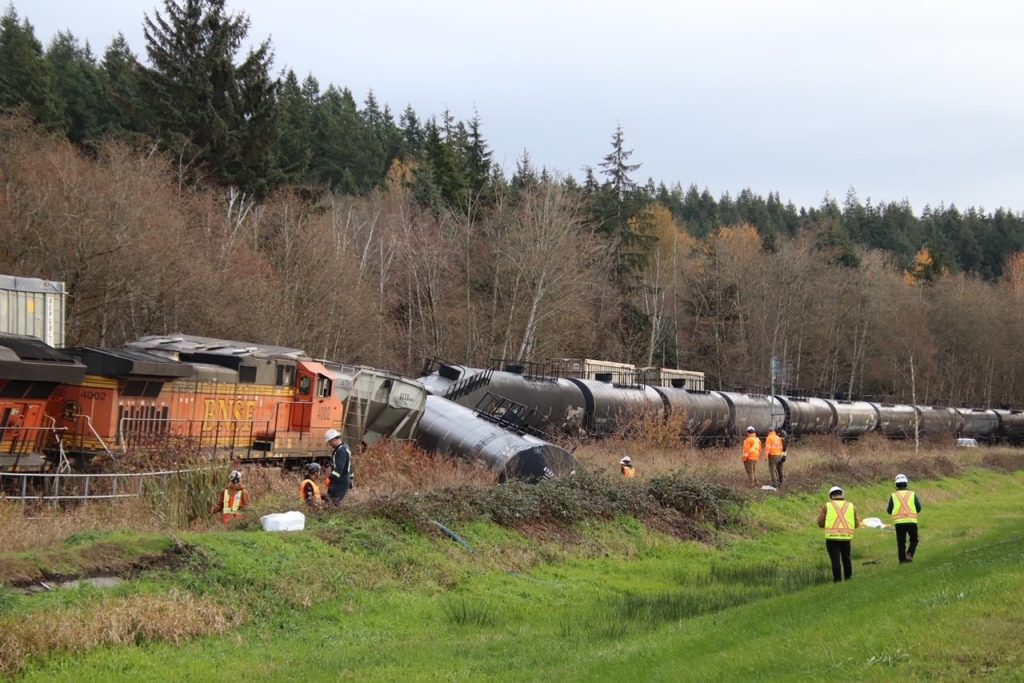 Several rail cars and machinery can be seen derailed in North Delta