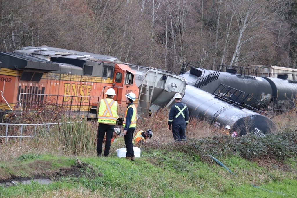 Several rail cars and machinery can be seen derailed in North Delta