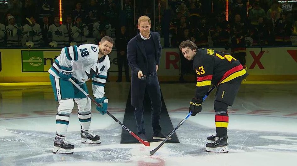 Quinn Hughes and Tomas Hertl line up for a ceremonial faceoff as Prince Harry prepares to drop the puck.