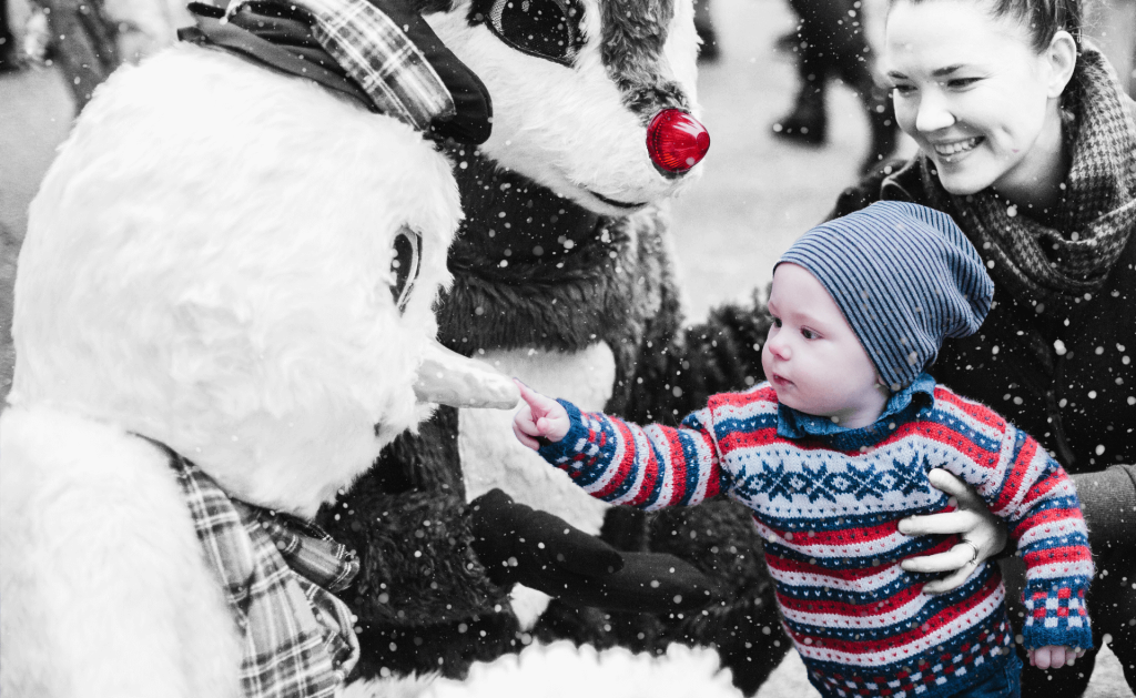 A child pokes at a stuffed snowman's nose