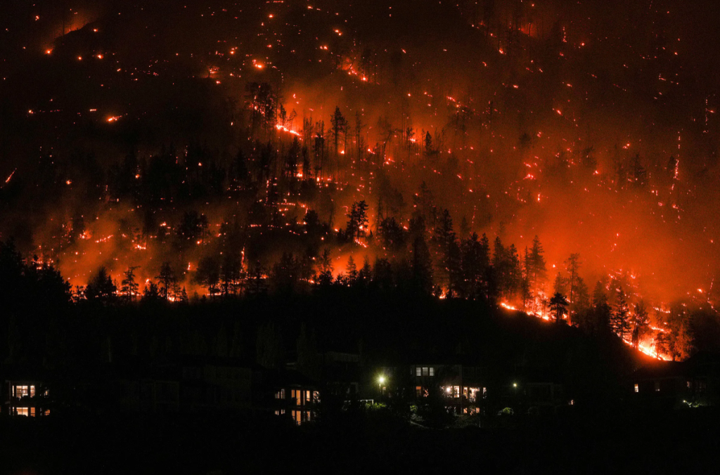 Flames from the McDougall Creek wildfire encircle a mountainside above homes in West Kelowna, British Columbia, on Aug. 18. Extreme weather conditions fueled Canada's worst wildfire season on record, with thousands of fires devastating millions of acres and darkening skies thousands of miles away. Darryl Dyck—The Canadian Press/AP