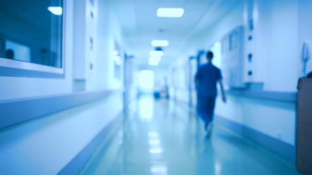 A health-care worker walks down a hospital hallway