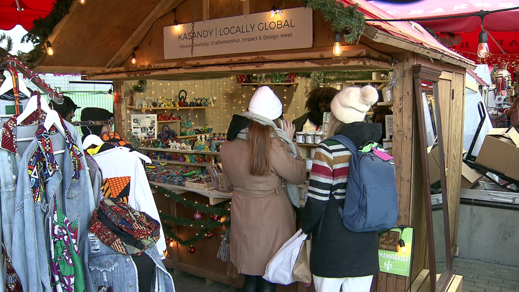 Patrons stand in front of Jackee Kasandy's booth at the Vancouver Christmas Market on Dec. 23, 2023.