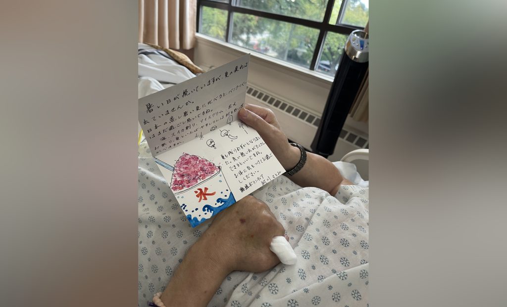 A senior reads a letter sent by a Tonari Gumi volunteer through one of its community support programs