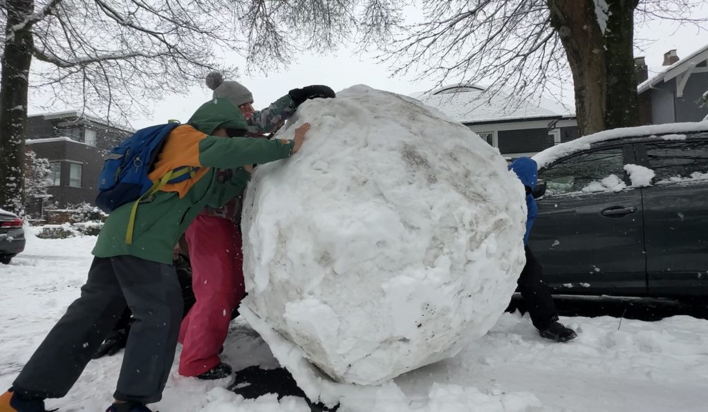 Some children in Vancouver make a giant snowball during a winter storm on Jan. 17, 2024