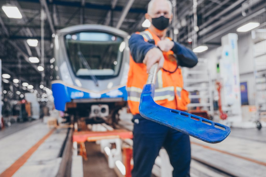 A TransLink SkyTrain vehicle technologist holds up a hockey stick used to clear ice and snow from SkyTrain doors