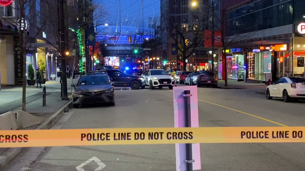Two SUV's are seen with multiple evidence markers surrounding them in Downtown Vancouver near Robson and Richards