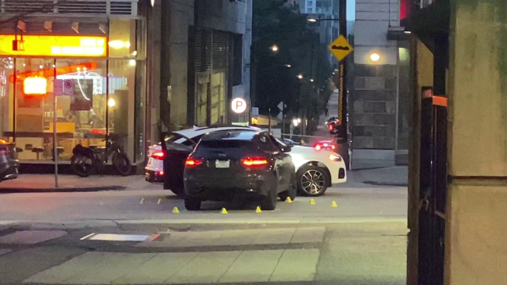 Two SUV's are seen with multiple evidence markers surrounding them in Downtown Vancouver near Robson and Richards