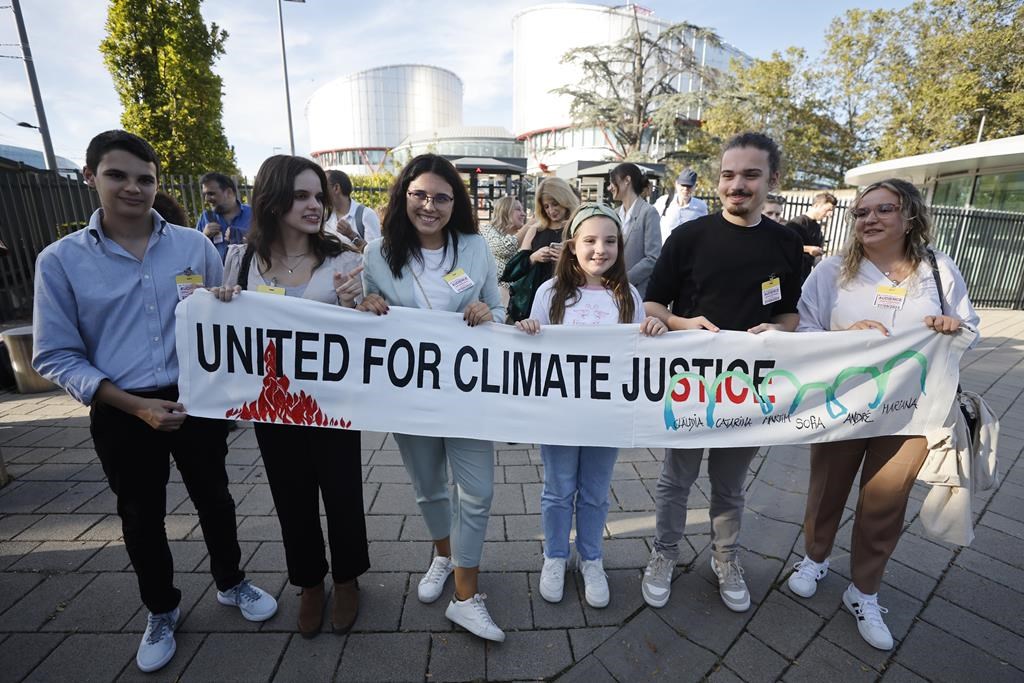 FILE - Mariana, center right, Claudia Agostinho, right, Martim Agostinho, second right, Sofia Oliveira, second left, her brother Andre, left, with Catarine Mota, pose with a banner outside the European Court of Human Rights on Sept. 27, 2023 in Strasbourg, eastern France. Europe’s highest human rights court will rule Tuesday April 9, 2024 on a group of landmark climate change cases aimed at forcing countries to meet international obligations to reduce greenhouse gas emissions.