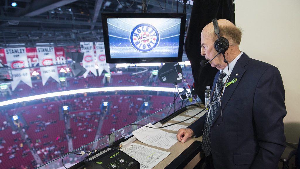 Bob Cole looks over his media desk onto a hockey arena