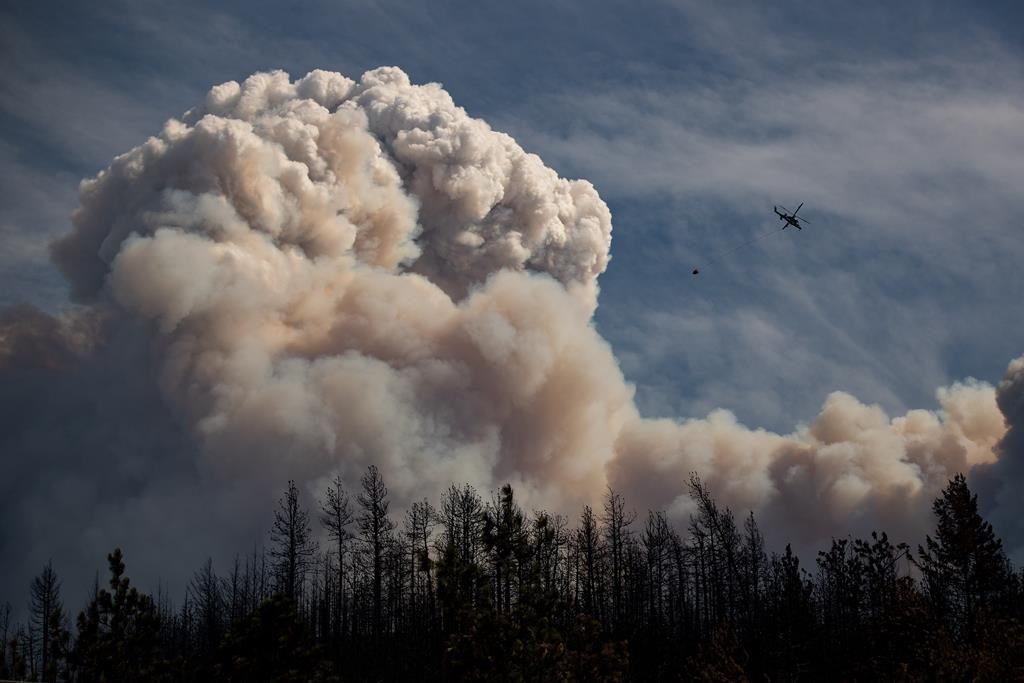 A helicopter flies near a cloud of smoke coming from the Lytton wildfire in 2021
