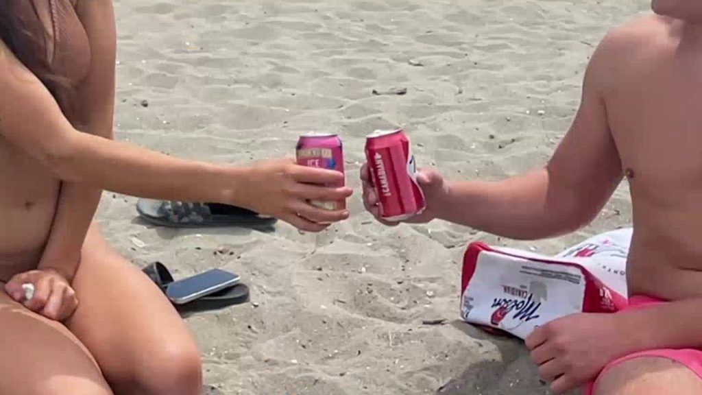 Two people are seen drinking on a Vancouver beach.