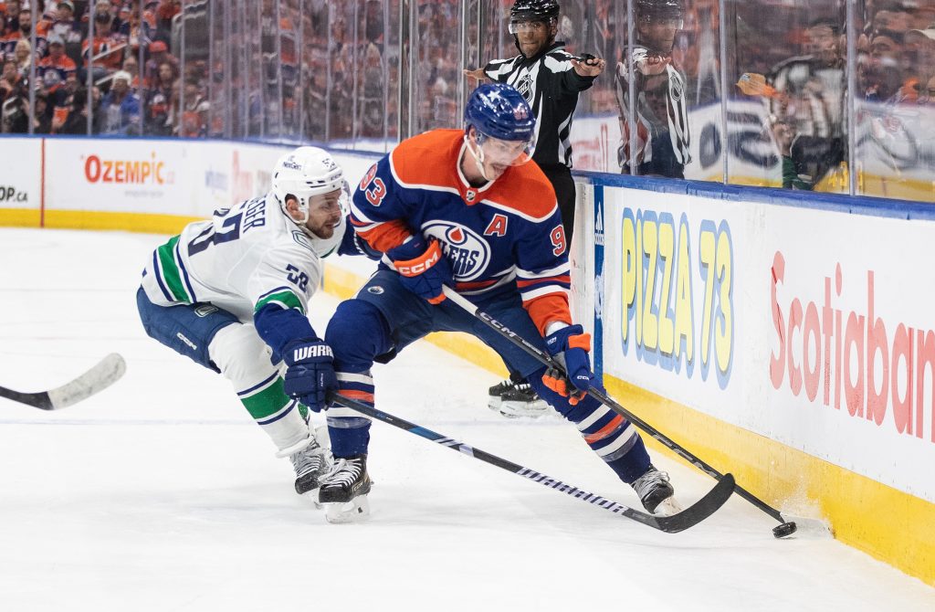 Vancouver Canucks' Teddy Blueger (53) and Edmonton Oilers' Ryan Nugent-Hopkins (93) battle for the puck during second period second-round NHL playoff action in Edmonton on Saturday May 18, 2024.