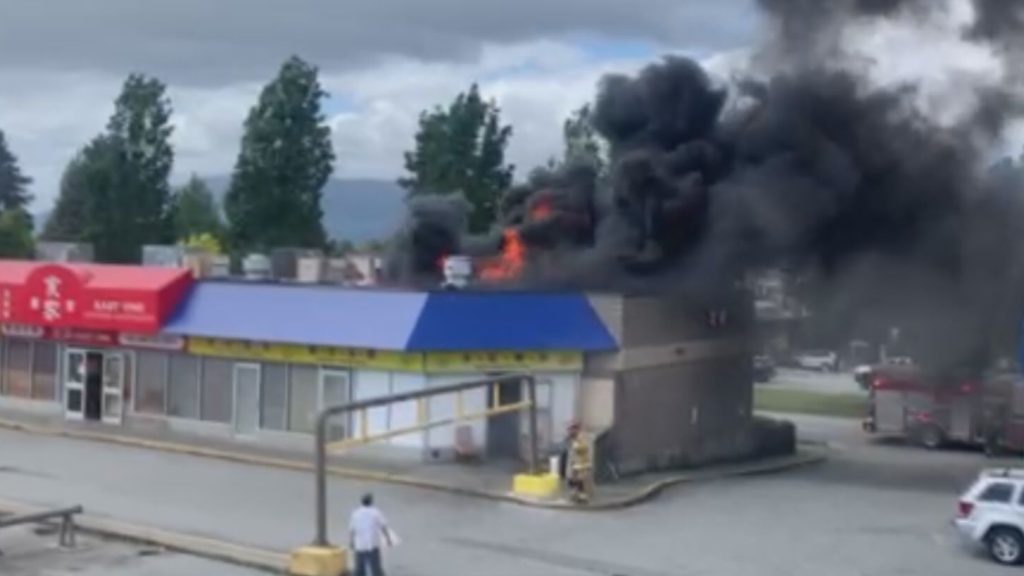 Flames and smoke can be seen on the roof of a building along East 1st Avenue in Vancouver