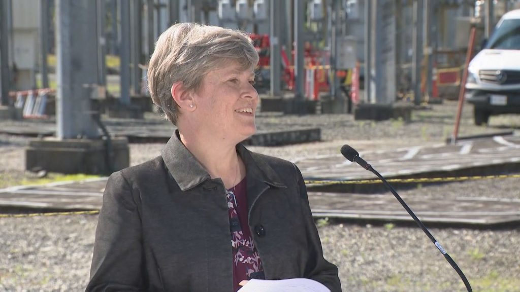 Josie Osborne speaking at a podium in front of the McLellan substation.