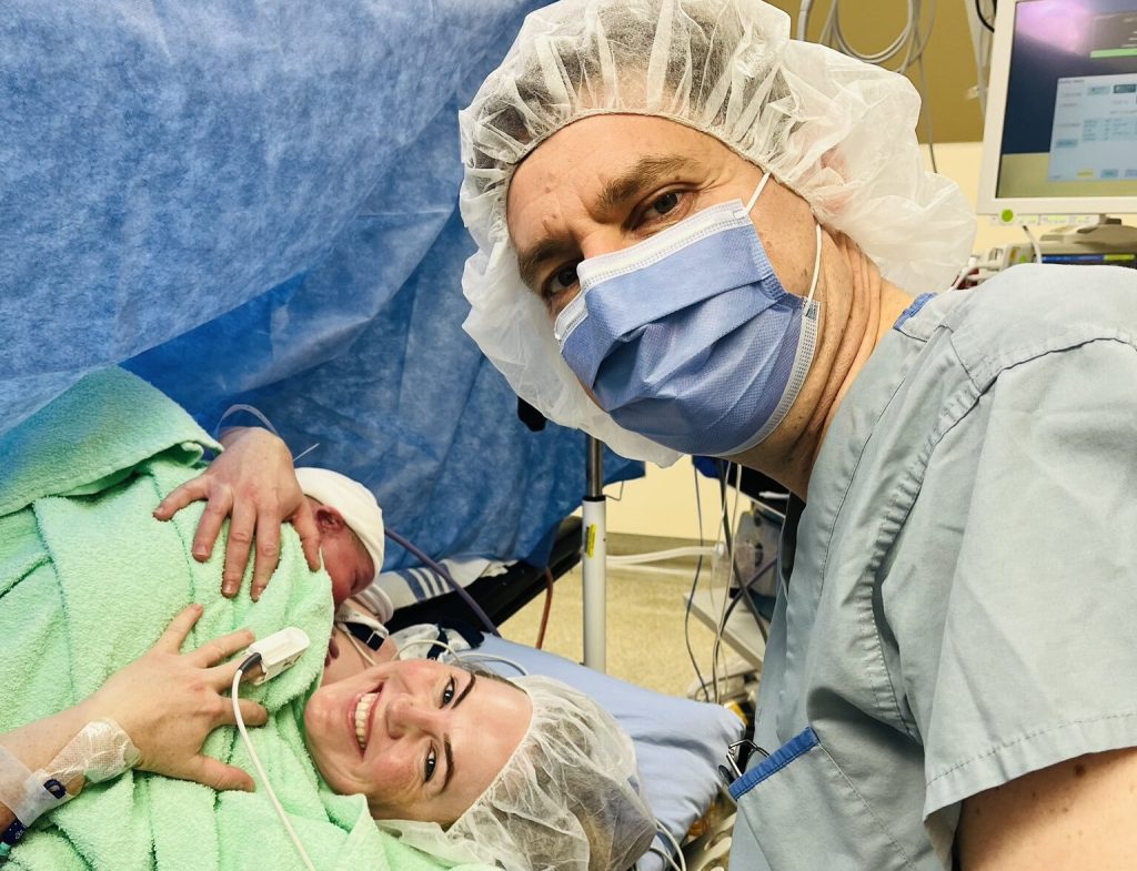 David Eby and Cailey Lynch pose with their newborn in a delivery room
