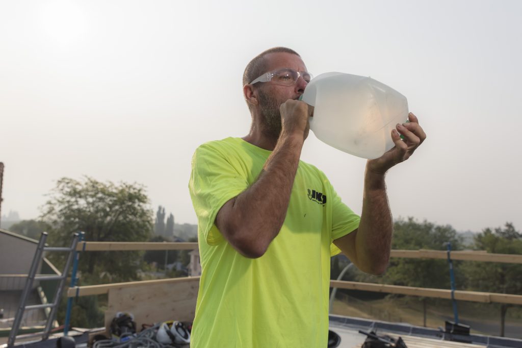 A worker drinks water from a jug