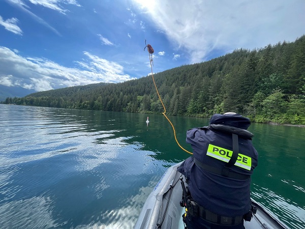 An RCMP officer throws a tow line into the water