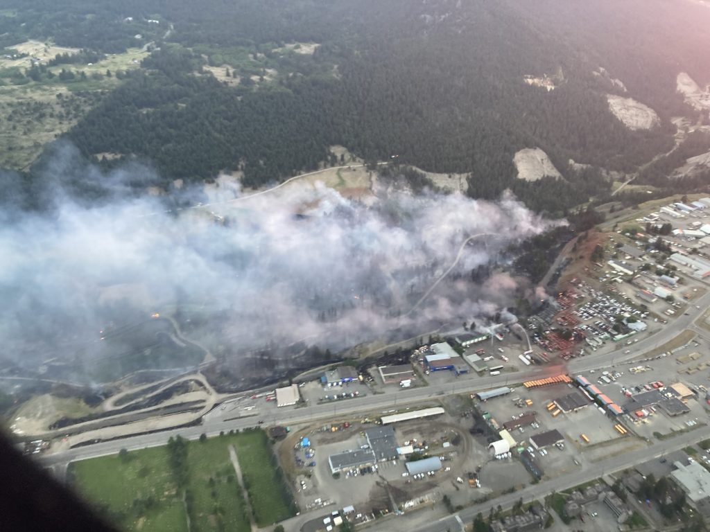This aerial shot from the BC Wildfire Service shows the fire in proximity to the City of Williams Lake. Red fire retardant can be seen on rooftops in the city's industrial area. (Courtesy BC Wildfire Service)