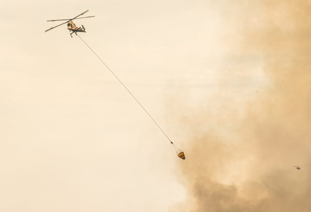 A helicopter is used to battle the Shetland Creek wildfire, near Kamloops, B.C., in a July 21, 2024, handout photo. The recent stretch of lightning and storms have pushed the number of wildfires burning in British Columbia past 400, and crews have increasingly turned to aircraft to battle the spike. THE CANADIAN PRESS/HO — BC Wildfire Service, *MANDATORY CREDIT*