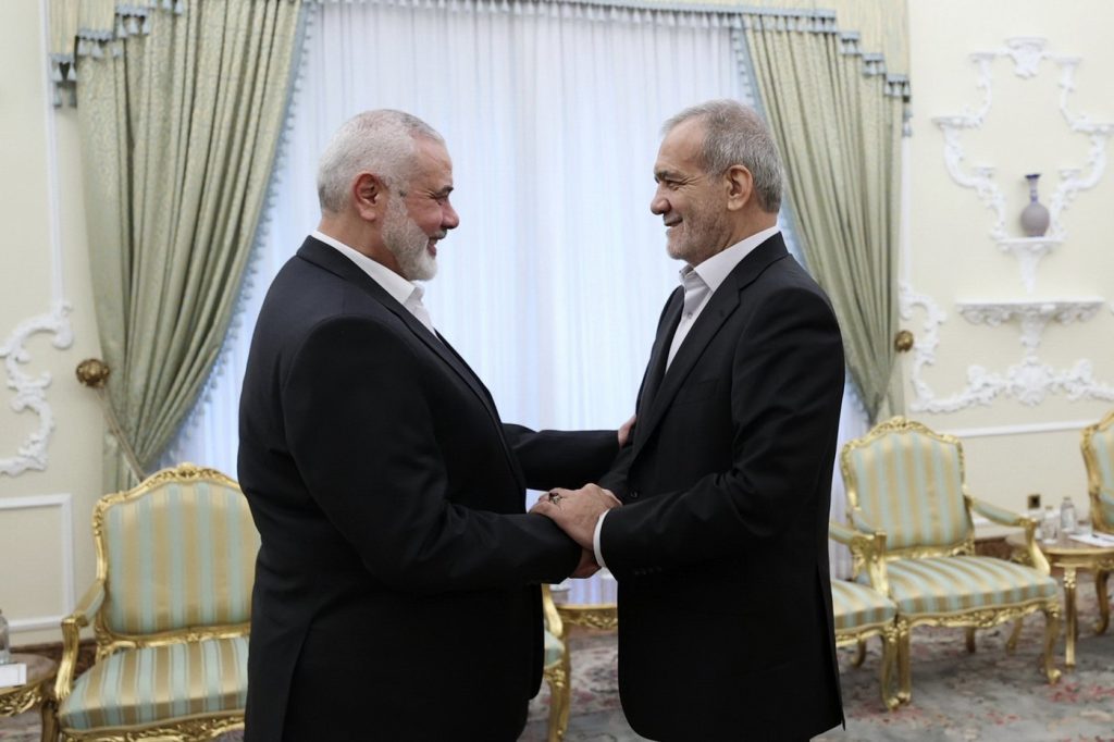 In this photo released by the Iranian Presidency Office, President Masoud Pezeshkian, right, shakes hands with Hamas chief Ismail Haniyeh at the start of their meeting at the President's office in Tehran, Iran, Tuesday, July 30, 2024.