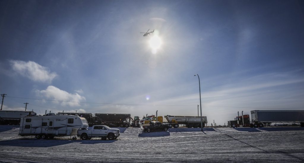 An RCMP helicopter flies over as a truck convoy of anti-COVID-19 vaccine mandate demonstrators block the highway at the busy U.S. border crossing in Coutts, Alta., Wednesday, Feb. 2, 2022. One of two men accused of conspiring to kill Mounties at the 2022 Coutts border blockade told his mother there "will be a war" should violence break out.
