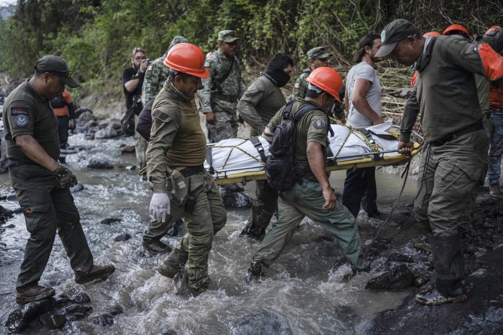 Rescuers recover the body of a policeman who state authorities said died in a car accident while checking damage caused by heavy rain in Alto Lucero, Veracruz, Mexico, Tuesday, July 2, 2024.