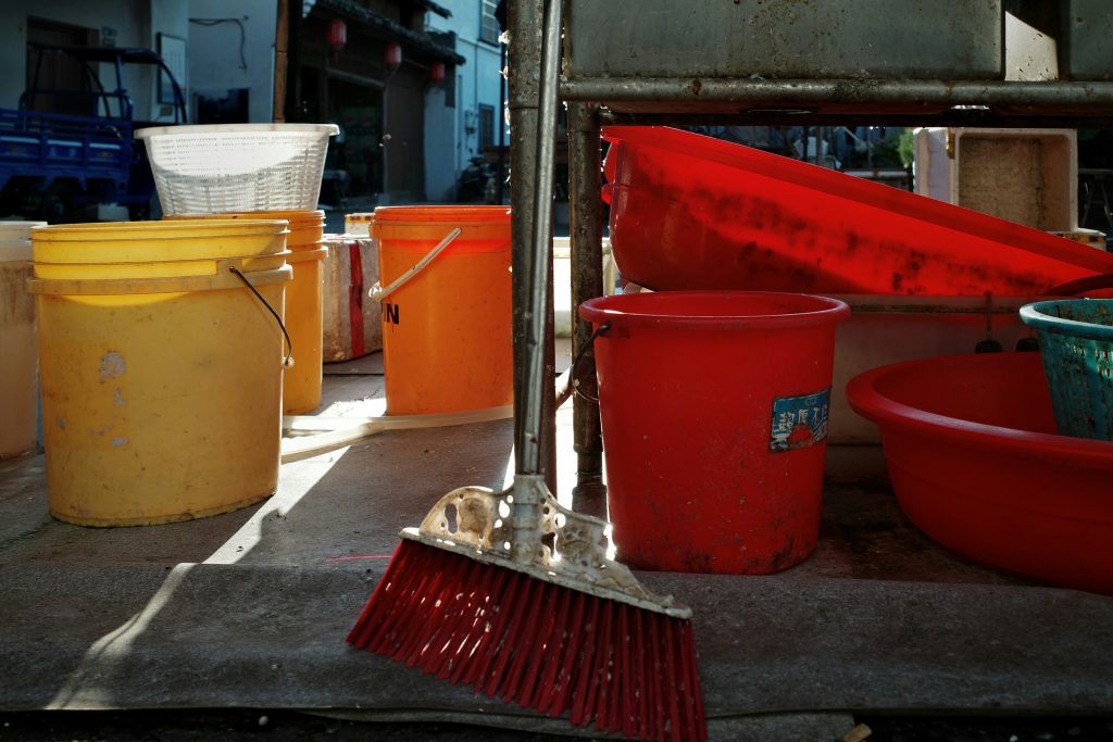 Multiple plastic buckets and a broom