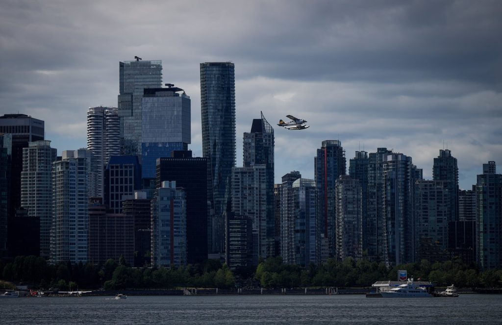 A plane flies in front of the Vancouver skyline