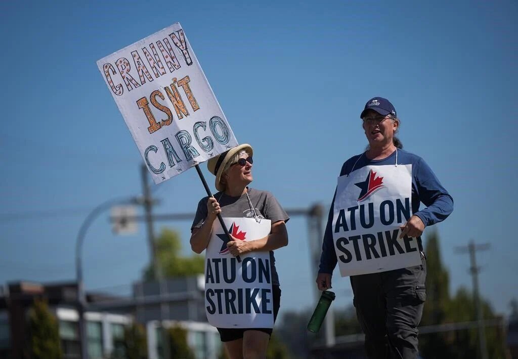 Two people rally for HandyDART workers, carrying signs