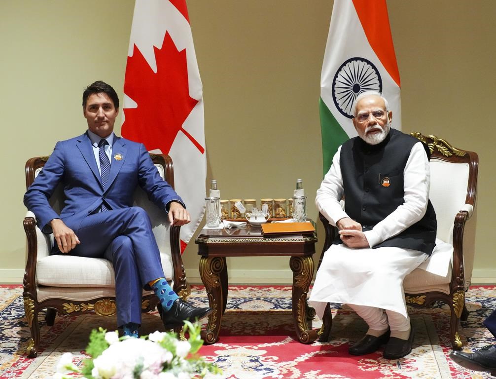 Justin Trudeau and Indian PM Narendra Modi sit together at a conference