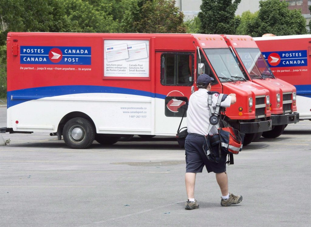 A postal worker walks past Canada Post trucks