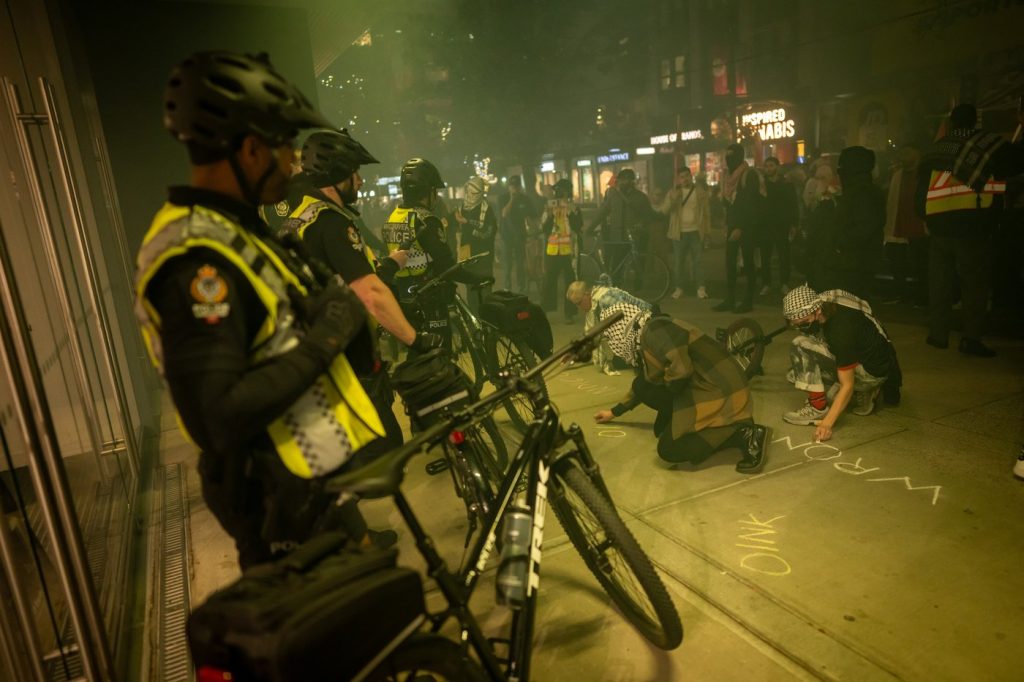 People write in chalk outside of a building during a pro-Palestine rally marking the anniversary of a Hamas attack on Israel in Vancouver, B.C., Monday, Oct. 7, 2024. THE CANADIAN PRESS/Ethan Cairns