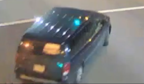 a black Dodge Grand Caravan with a distinctive, white sign covering the rear passenger-side window