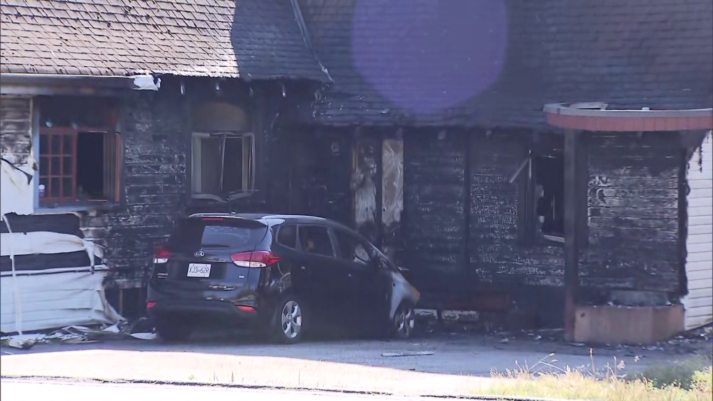 A vehicle parked outside the burned exterior of a former church building