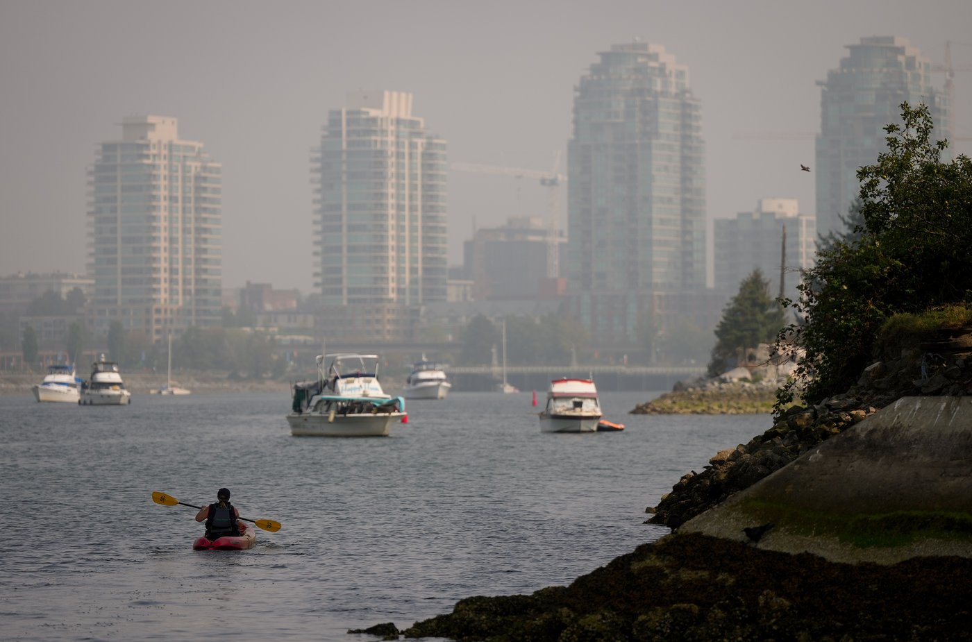 A woman paddles a kayak on False Creek as smoke from wildfires burning in B.C. and the U.S. hangs in the air, in Vancouver, B.C., Wednesday, Sept. 3, 2025. THE CANADIAN PRESS/Darryl Dyck
