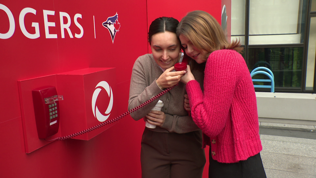 Baseball fans use the dugout phone at the Rogers “Dial the Dugout” popup at Vancouver's CF Pacific Centre on Oct. 15, 2025