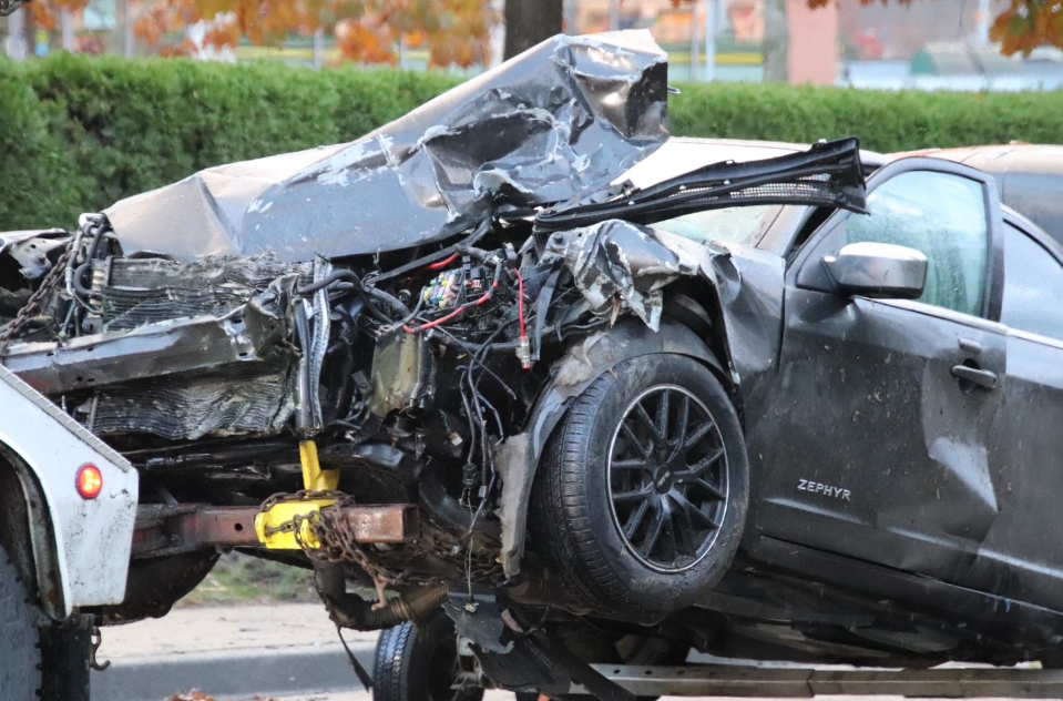 A badly damaged black sedan