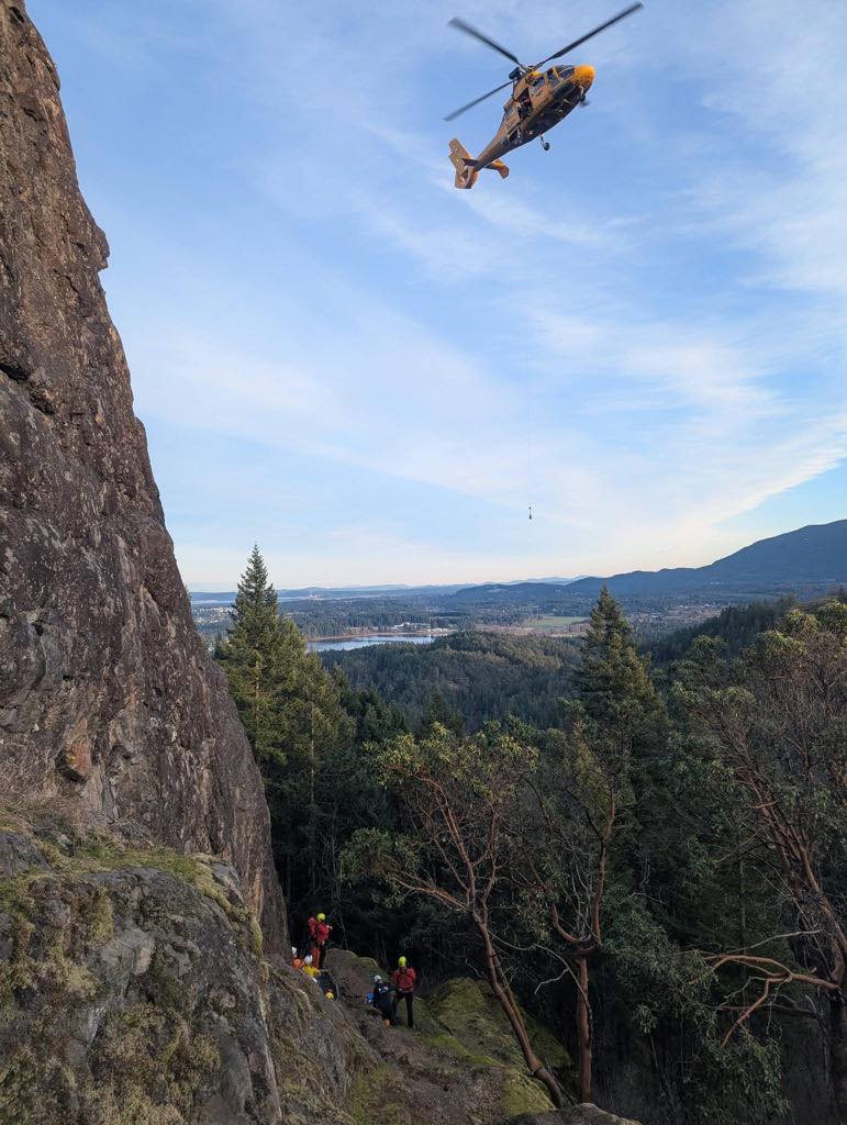 A helicopter flies above an injured climber on a mountain ridge