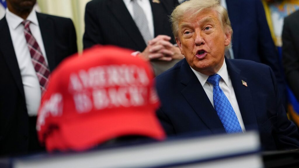 President Donald Trump speaks alongside a red cap stating "America Is Back!" in the Oval Office of the White House, Friday, June 26, 2026, in Washington. (AP Photo/Julia Demaree Nikhinson)
