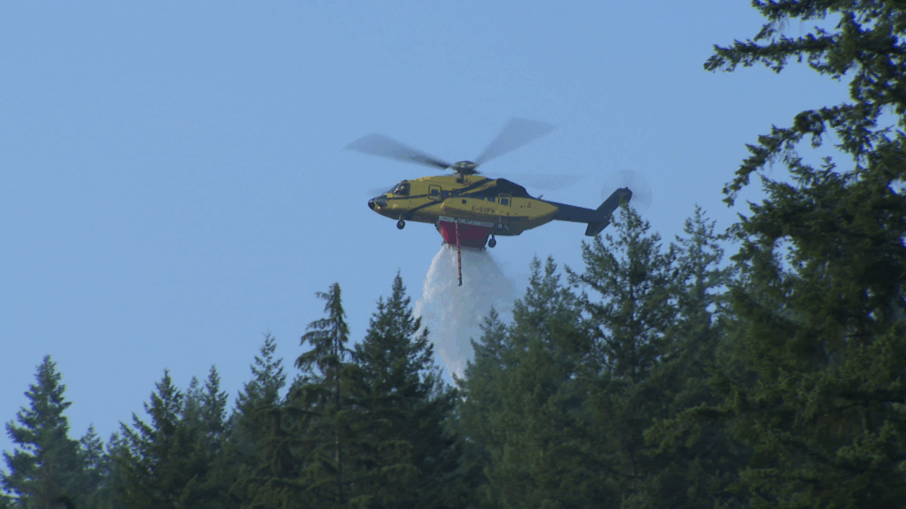 A helicopter drops water on a wildfire in Belcarra Regional Park on Wednesday August 5, 2026.